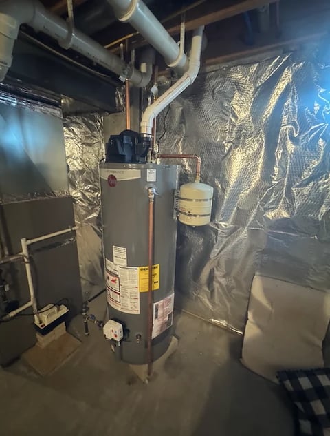 Gas water heater in basement with piping, expansion tank, and insulated ductwork